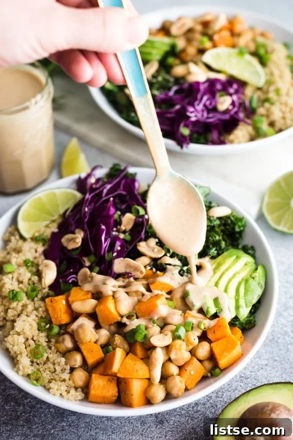 Close-up of creamy peanut sauce being drizzled over a vibrant sweet potato and chickpea buddha bowl.