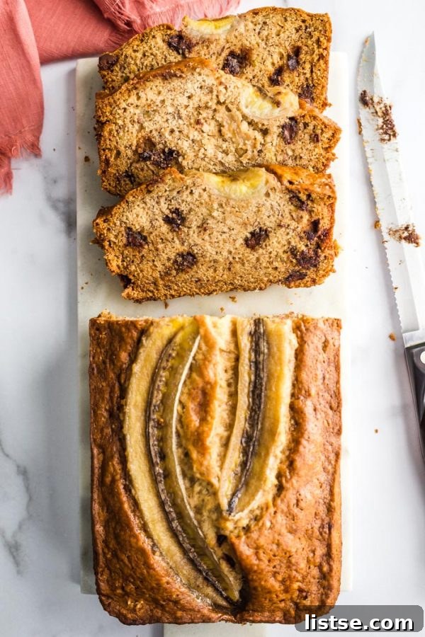 A freshly baked loaf of vegan chocolate chip banana bread, still in its loaf pan, cooling on a wire rack.