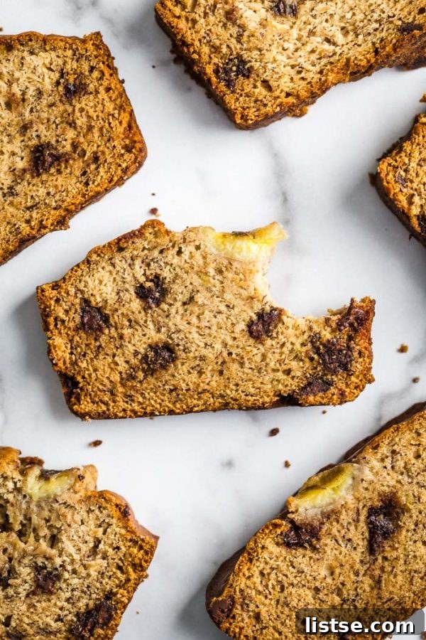 Various slices of chocolate chip vegan banana bread artfully arranged on a cutting board, garnished with fresh banana slices and chocolate chips, ready to be served.