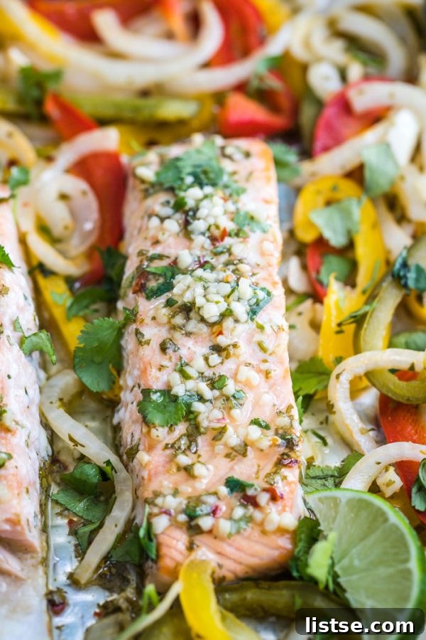 Various ingredients for Sheet Pan Garlic Lime Salmon, including salmon fillets, bell peppers, limes, and fresh cilantro, on a wooden cutting board.