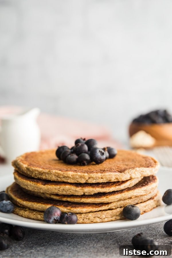 Vegan eggless protein pancakes topped with vibrant blueberries and maple syrup.
