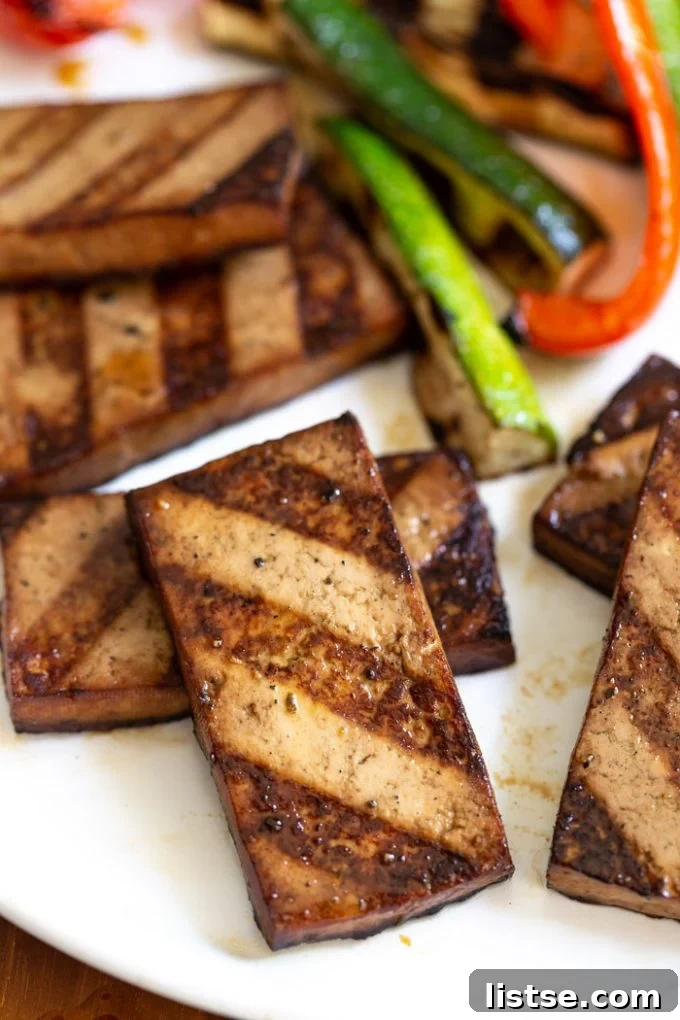 Flavorful Grilled Tofu 2 Perfectly grilled tofu slices on a hot grill grate, showing appealing char marks and a golden-brown texture, ready for a delicious and healthy summer meal.