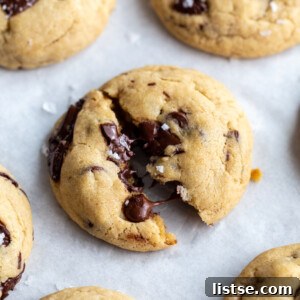 Decadent Vegan Chocolate Chip Cookies 12 chocolate chunk cookies on a white background. the middle cookie is slightly cracked in half with melted chocolate coming out