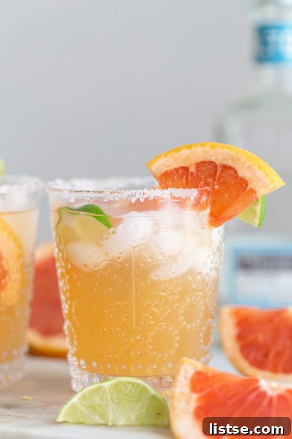 Grapefruit Sunset Margarita 2 A vibrant Grapefruit Margarita in a salt-rimmed glass, garnished with a fresh grapefruit slice, perfect for summer.