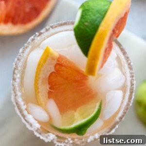 Two vibrant grapefruit margaritas in salt-rimmed glasses.