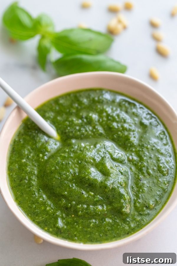 Plant-Powered Pesto 2 Vegan pesto sauce in pink bowl, garnished with fresh basil leaves and pine nuts.