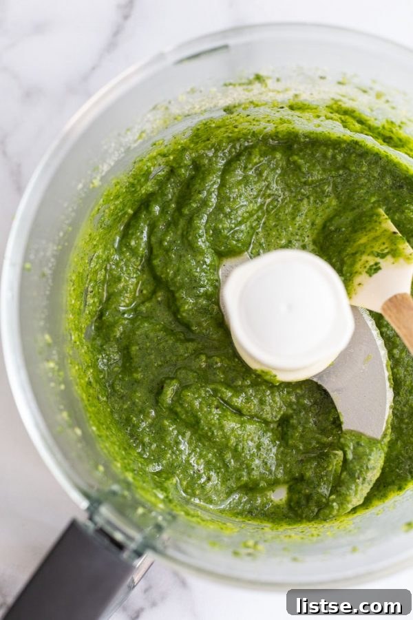 Plant-Powered Pesto 3 Close-up shot showing how to make vegan pesto, with basil leaves, garlic, and pine nuts in a food processor.