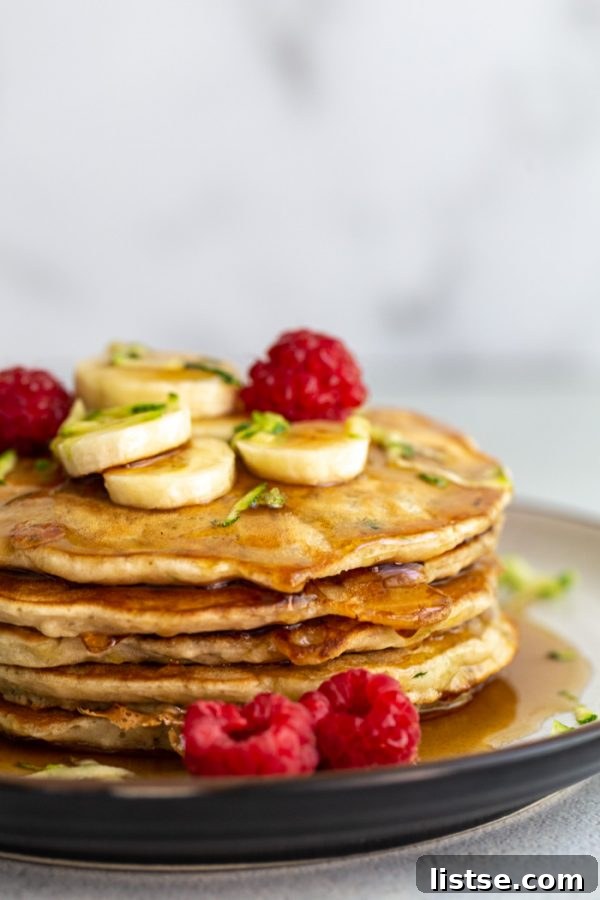 Savory Zucchini Fritters 2 Fluffy vegan zucchini pancakes topped with fresh berries and maple syrup, a perfect summer breakfast.