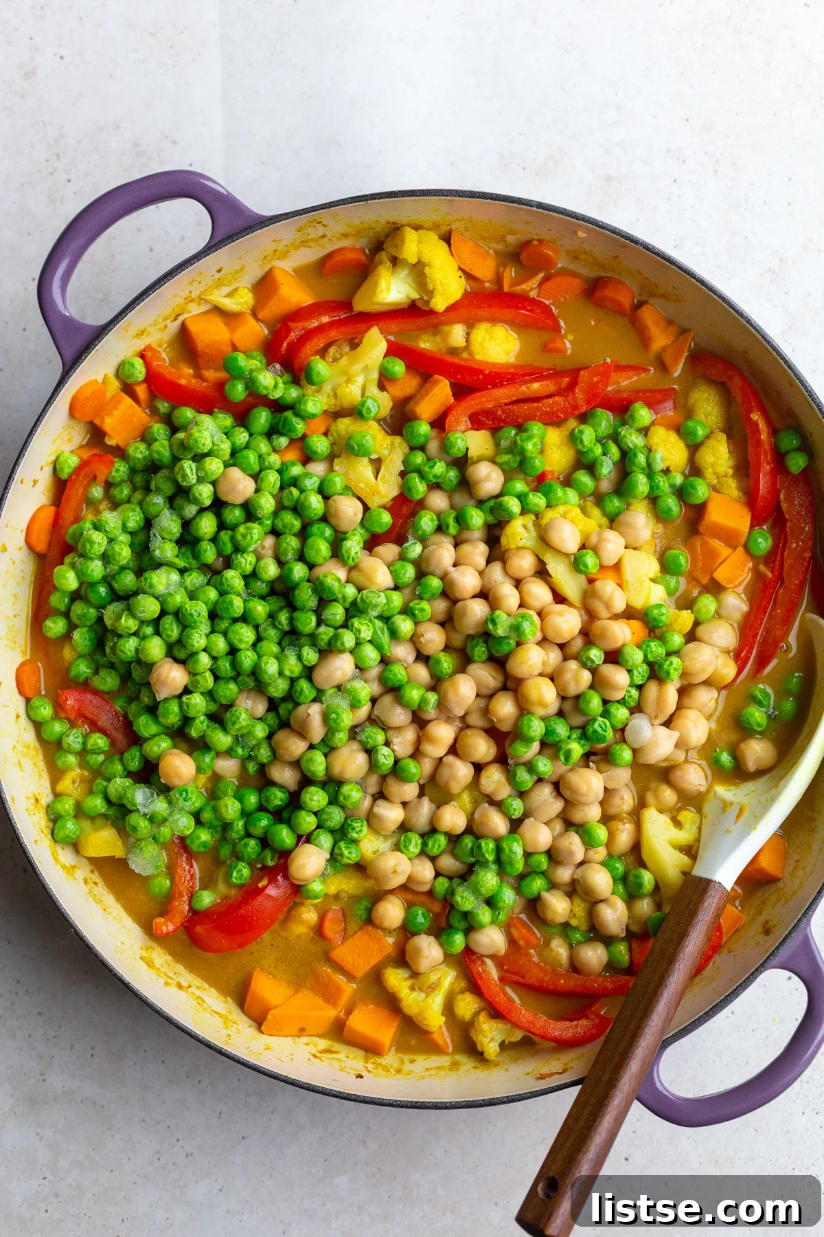 Golden Vegan Chickpea and Sweet Potato Coconut Curry 8 Cooked sweet potato curry in a skillet with chickpeas and green peas freshly added on top, awaiting a final stir.