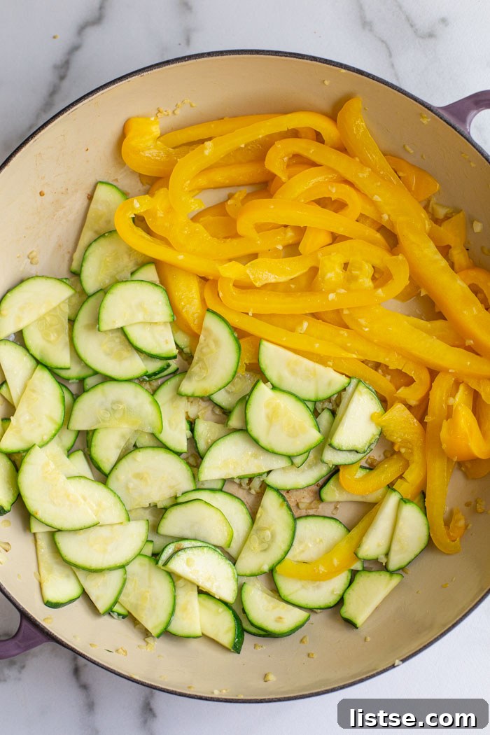 Sautéing yellow bell pepper and zucchini in a skillet until softened.