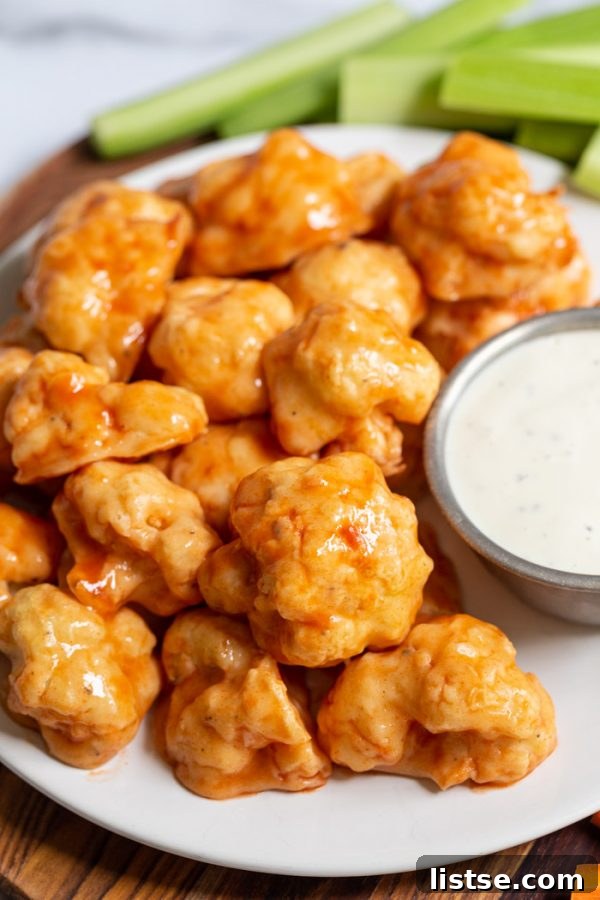 A vibrant plate of buffalo cauliflower wings served with ranch dip and fresh celery sticks.