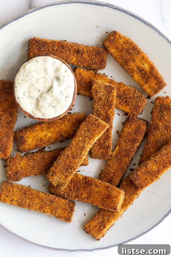 Delicious and crispy vegan tofu fish sticks with a side of dipping sauce, perfect for a plant-based meal.