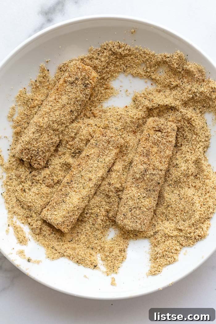 A plate of freshly baked, golden-brown vegan tofu fish sticks ready to be served.