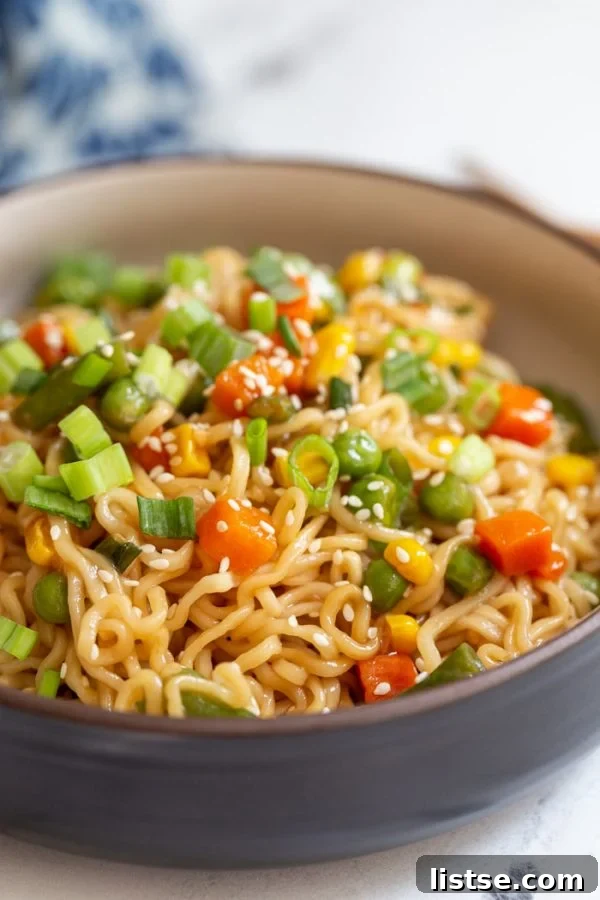 A bowl of ramen stir fry, highlighting the fresh green onions and other cooked vegetables, with chopsticks ready for serving.