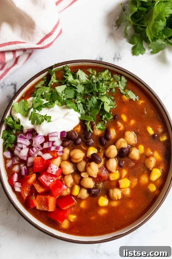 A vibrant bowl of chickpea taco soup rests on a polished marble countertop, ready to be enjoyed.