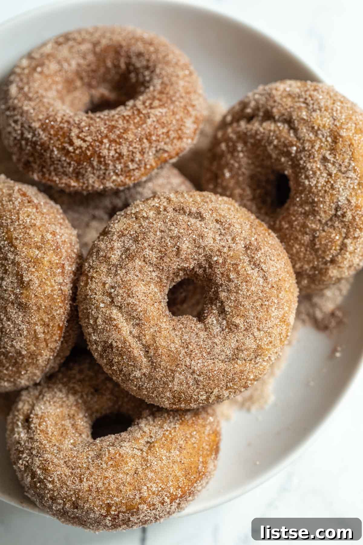 A bowl of cinnamon sugar coated baked vegan donuts stacked invitingly, ready to be served for breakfast or brunch.