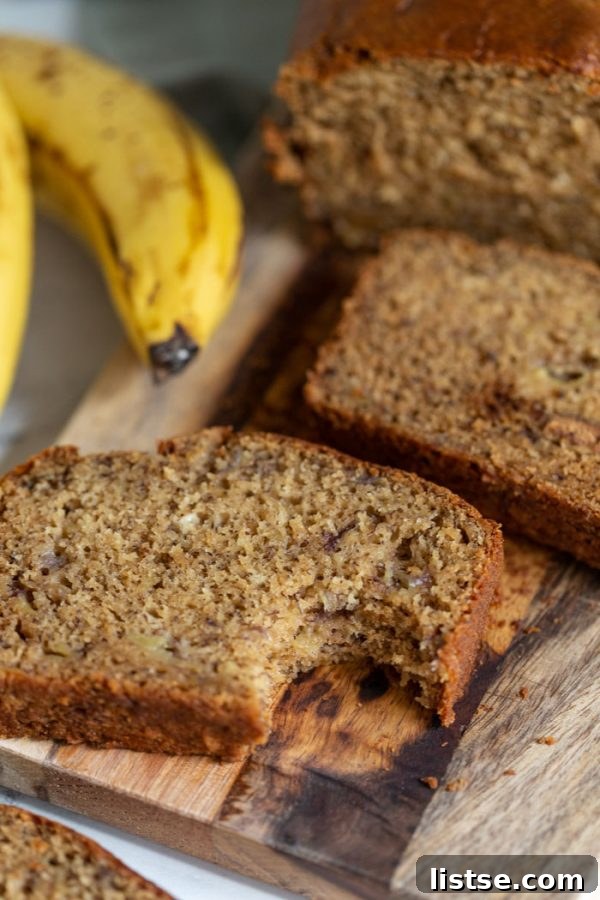 Plant-Powered Banana Loaf 4 A slice of vegan banana bread on a wooden board with a bite taken out, showing its moist texture.