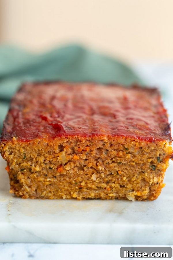A slice of hearty Vegan Meatloaf on a plate, showcasing its appealing texture and rich color, ready to be served. A delicious and satisfying plant-based main course. #veganfood #meatloafrecipe