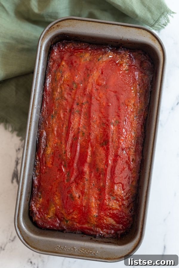 A freshly baked Vegan Meatloaf, topped with a rich ketchup glaze, ready to be sliced and served. This plant-based recipe is a perfect comfort food. #veganmeatloaf #comfortfood