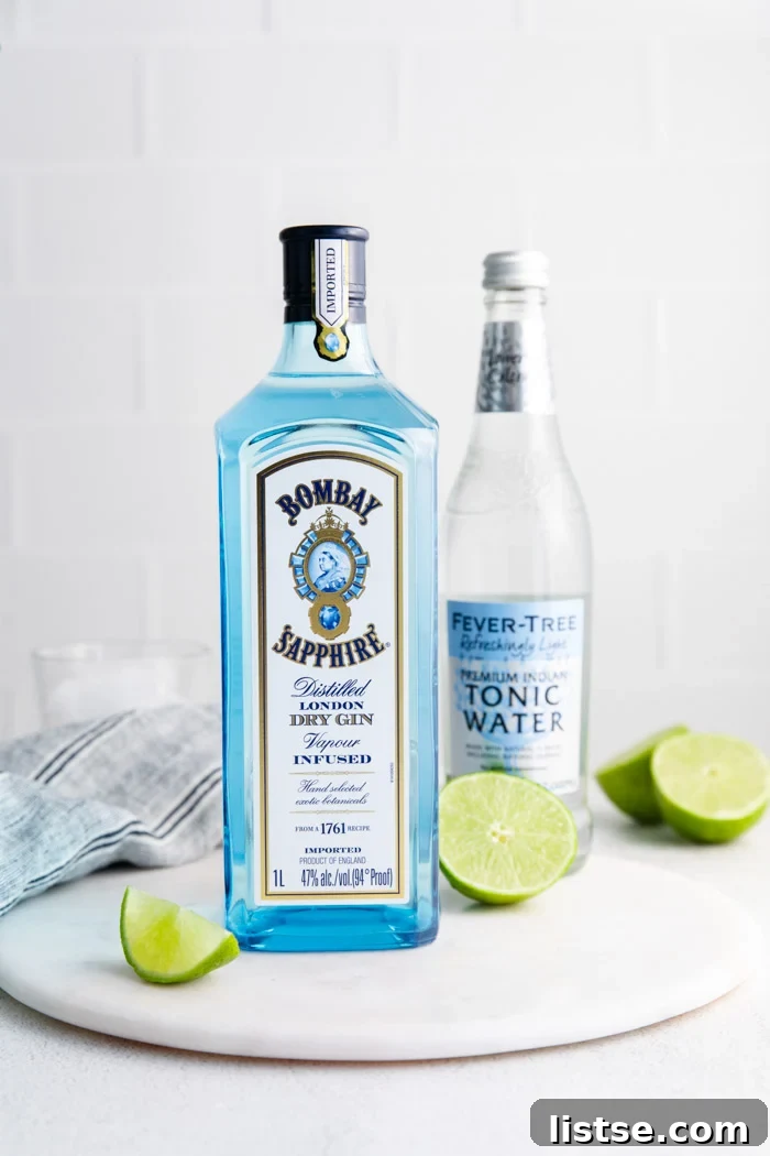 bombay saffire with limes around it and a bottle of fever hill tonic water in the background. ingredients for gin and tonic