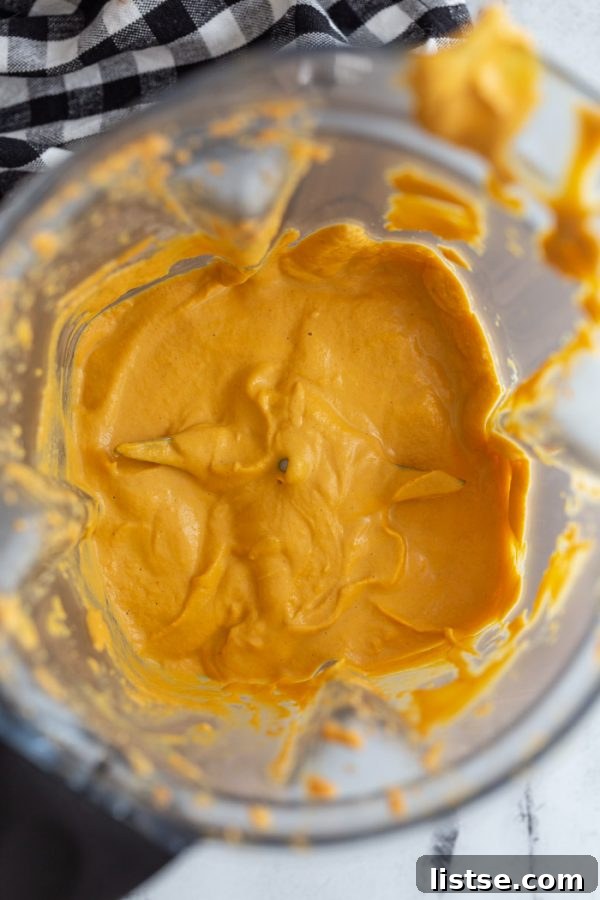 Vegan mac and cheese sauce being blended to a smooth, creamy consistency in a blender.