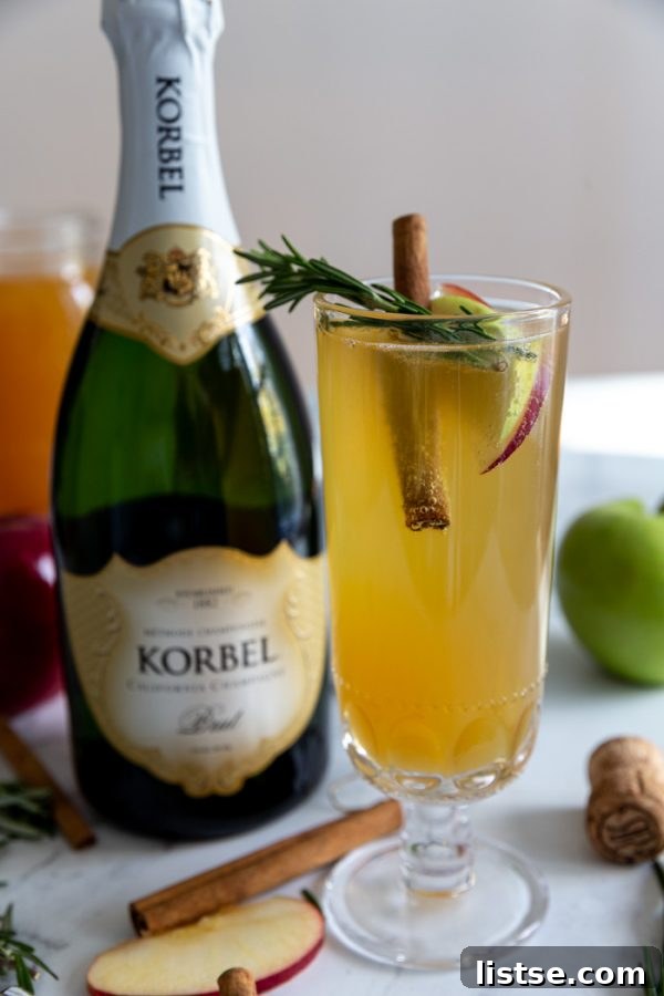 Two glasses of sparkling Apple Cider Mimosas garnished with cinnamon sticks and apple slices, set against a festive autumn backdrop.