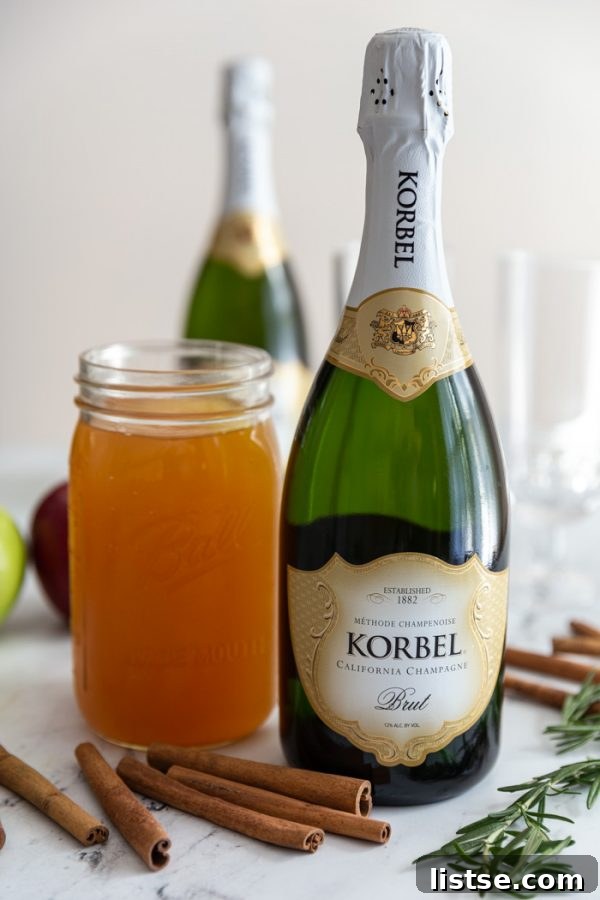 A festive close-up of an Apple Cider Mimosa, garnished with a cinnamon stick, fresh rosemary, and an apple slice, embodying the holiday spirit.