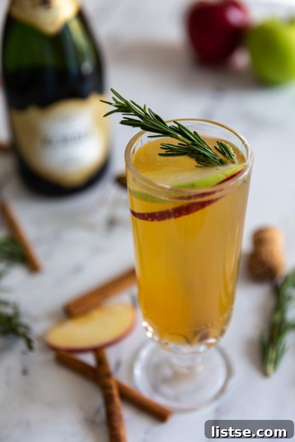 An inviting overhead shot of Apple Cider Mimosas, garnished with fresh rosemary, cinnamon, and apple slices, perfectly capturing the holiday spirit.