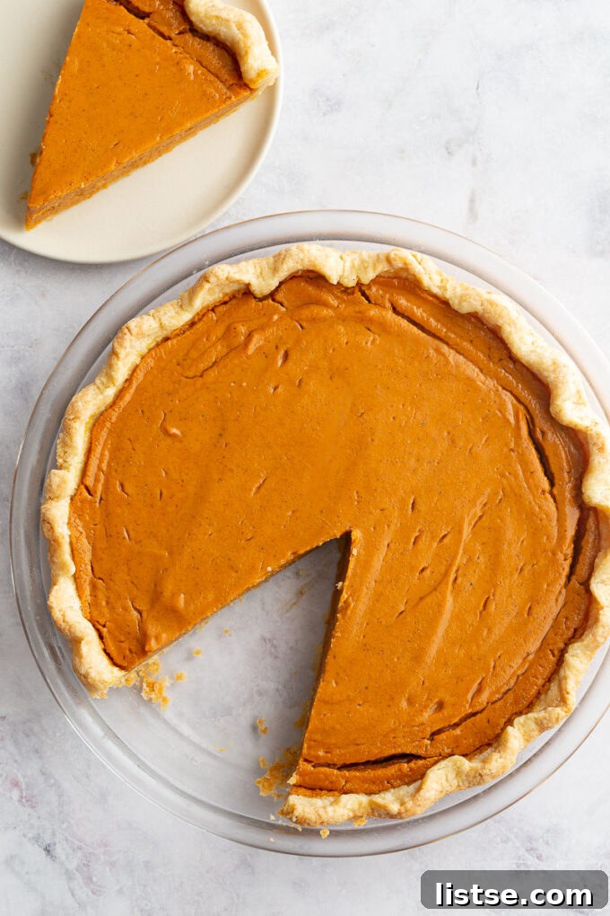 Golden Sweet Potato Heaven 7 sweet potato pie with a slice taken out and sitting in the corner of the shot on a small plate