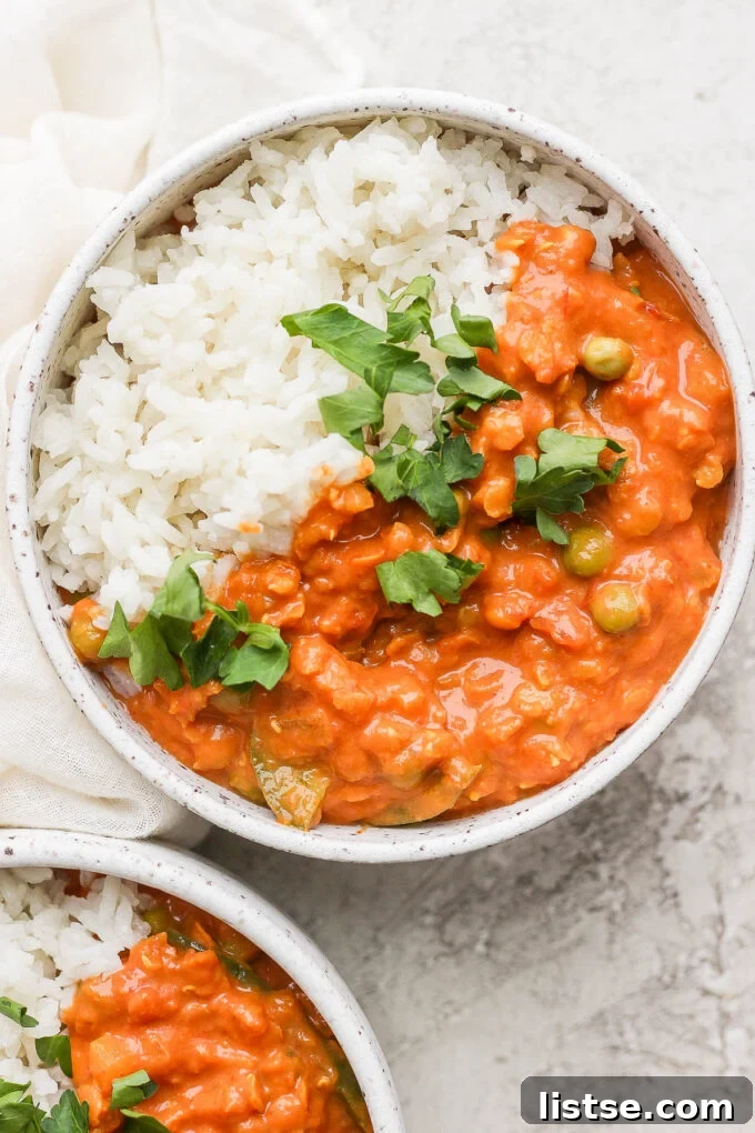 Lentil curry served over fluffy coconut rice, garnished with fresh herbs.