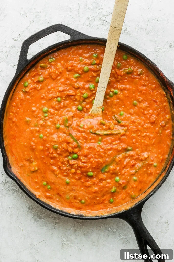 Stirring the finished coconut lentil curry in a large pan.