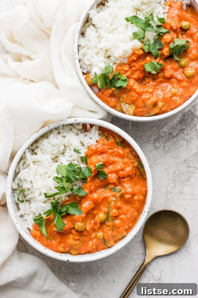 Two bowls of coconut lentil curry served alongside coconut rice.