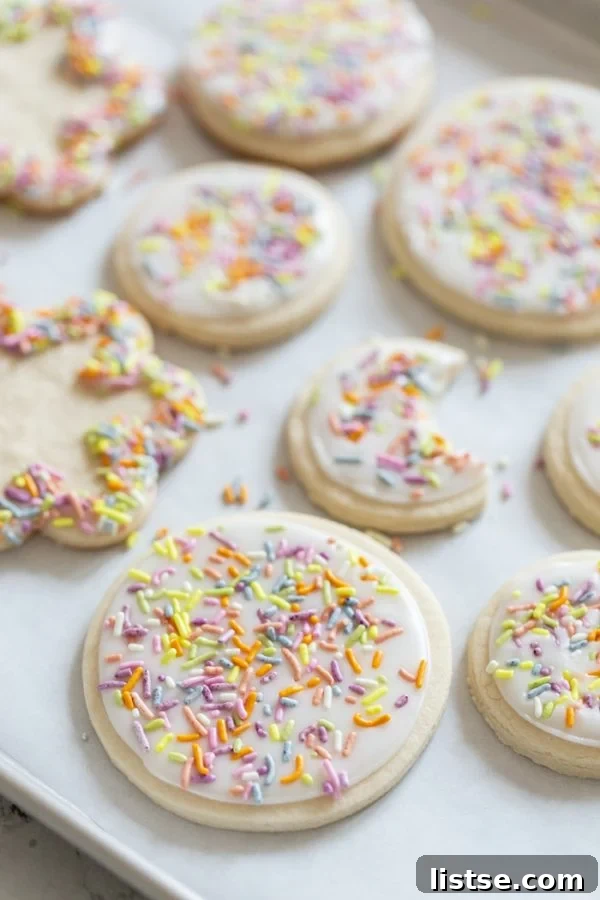 vegan sugar cookies with icing and sprinkles on a wooden board