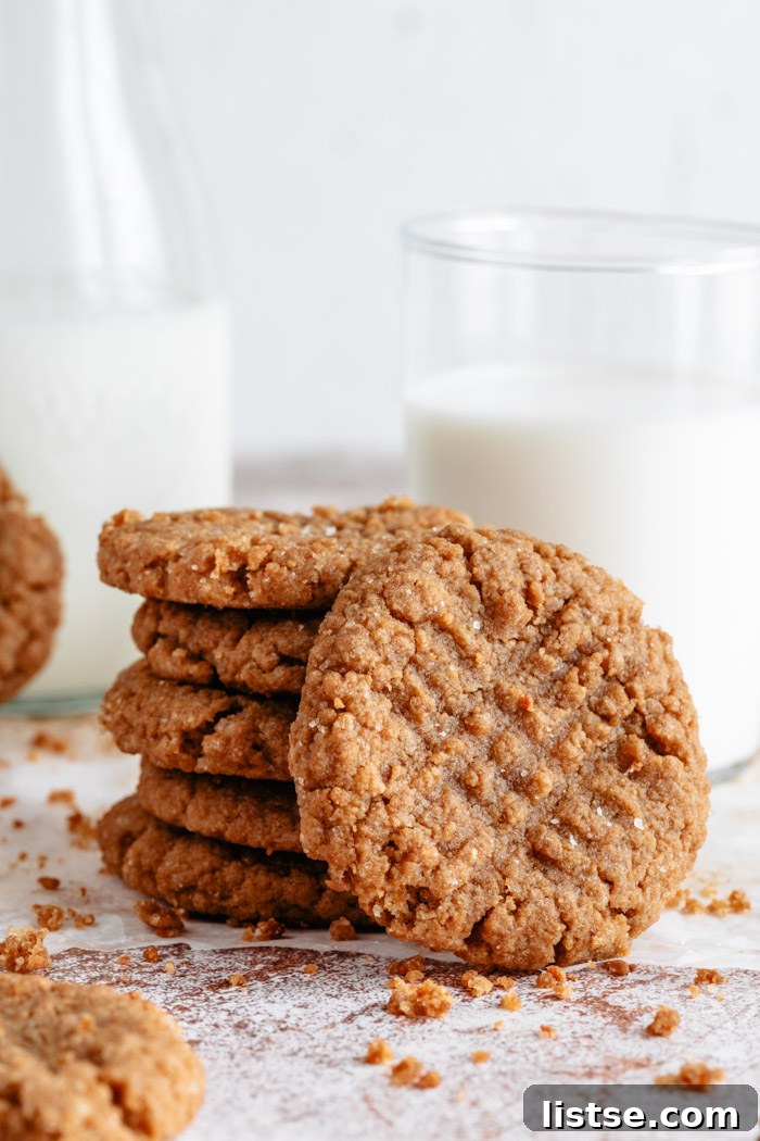 A stack of perfectly baked vegan peanut butter cookies resting beside a refreshing glass of plant-based milk, ready to be enjoyed as a classic pairing.