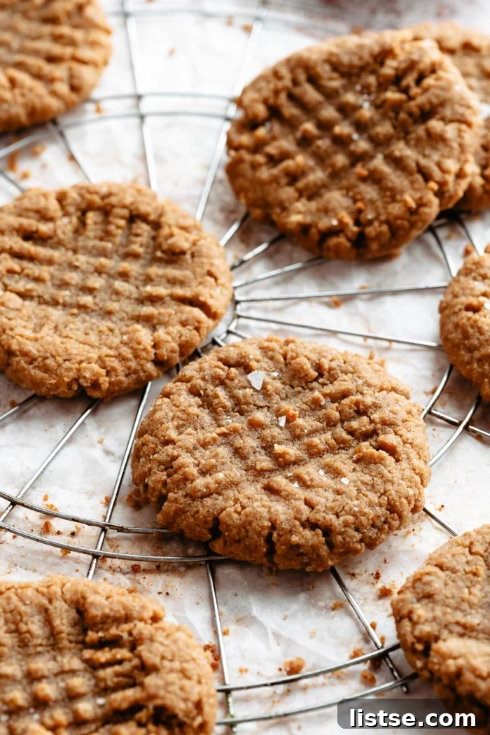 A close-up shot of vegan peanut butter cookies, artfully arranged on a white background with a cooling rack, highlighting their perfect texture and golden hue.