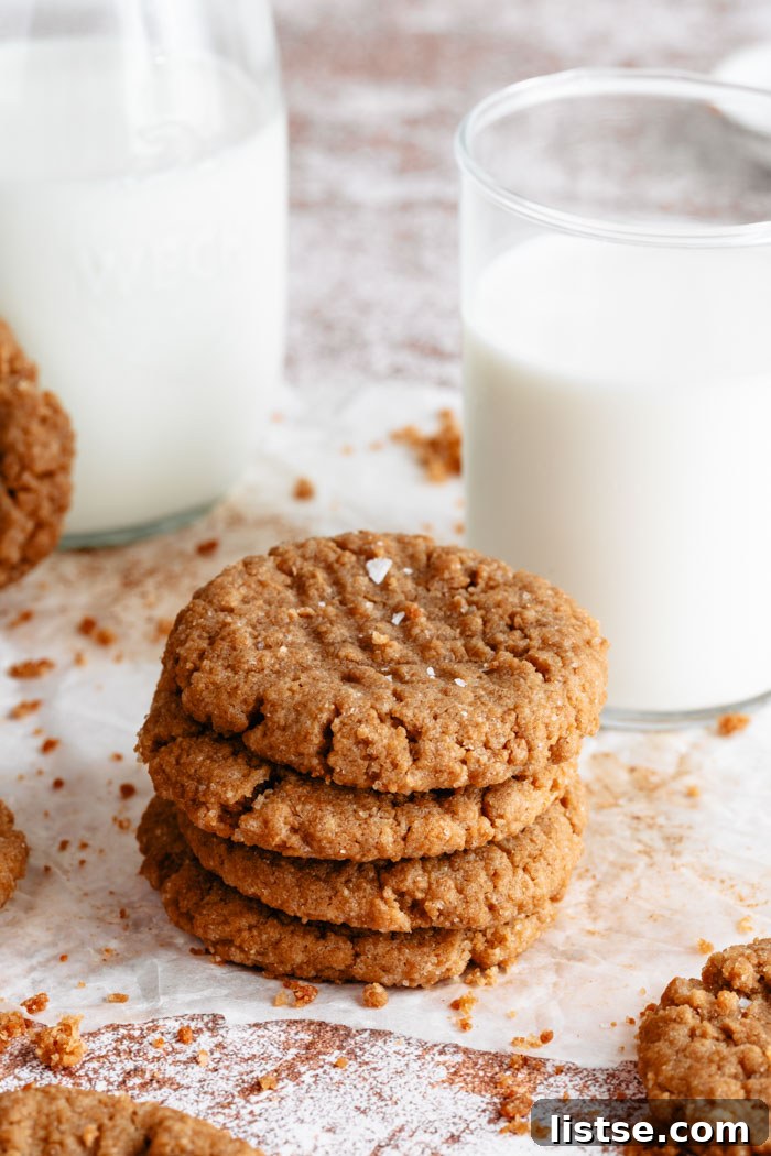A small, inviting stack of vegan peanut butter cookies next to a glass of cold plant-based milk, highlighting their rustic charm and delicious appeal.