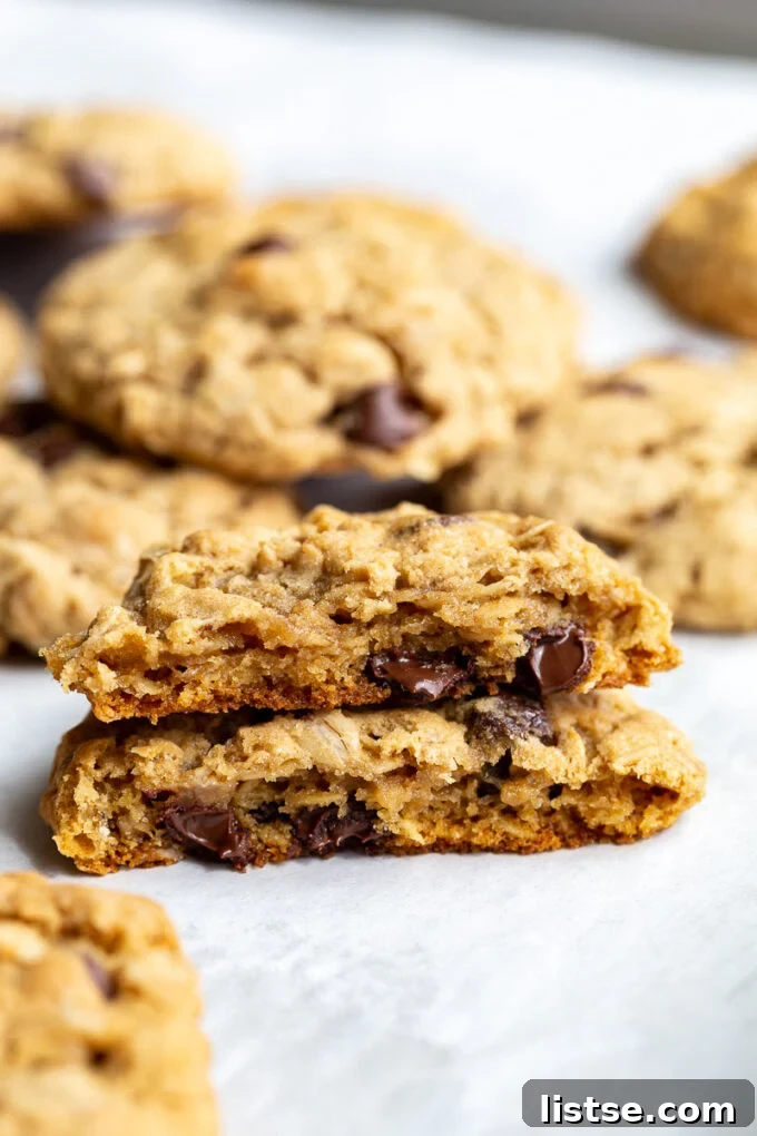 A vegan oatmeal cookie cut in half and stacked, revealing its soft, chewy interior with oats and mix-ins visible.