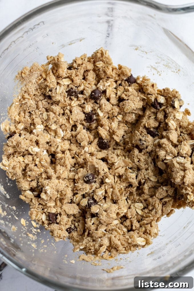 Smooth and ready-to-bake vegan oatmeal cookie dough in a clear glass bowl, showcasing its perfect consistency.