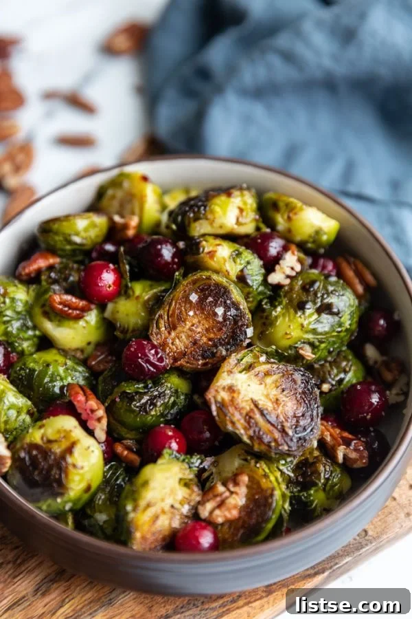 A bowl of roasted Brussels sprouts, fresh cranberries, and pecans, garnished with sea salt.