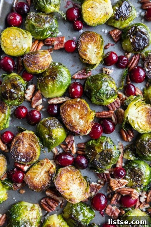 Close-up of cranberry Brussels sprouts on a baking tray, showing crispy edges and plump cranberries.
