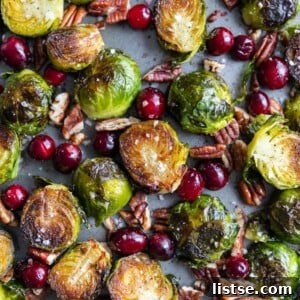 Sheet pan filled with roasted Brussels sprouts, fresh cranberries, and roasted pecans.