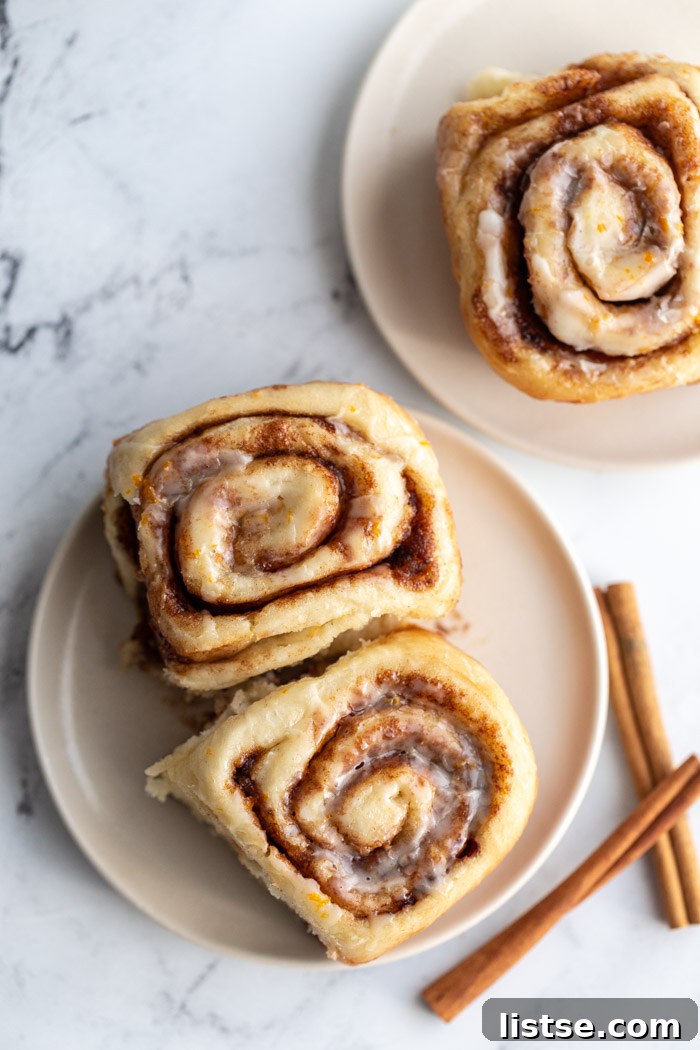 Irresistible Vegan Cinnamon Rolls 4 vegan cinnamon rolls on a plate with cinnamon sticks nearby