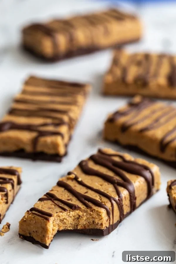 A 45-degree shot of homemade vegan protein bars, one with a bite taken out, showing the delicious plant-based filling and chocolate drizzle.