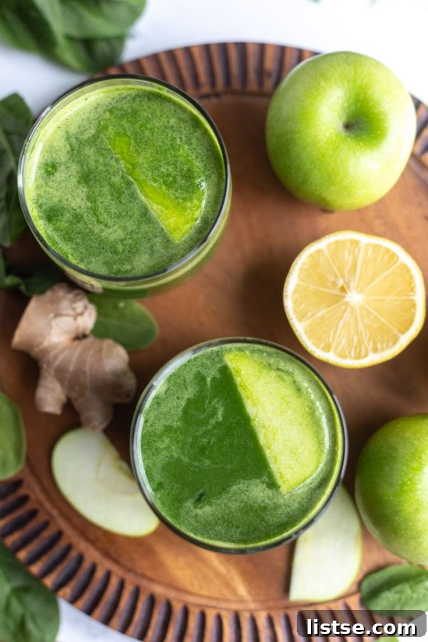 Green Apple Revival 3 An overhead shot of two glasses of apple green juice, garnished with fresh apple slices, on a rustic wooden board, ready for enjoyment.