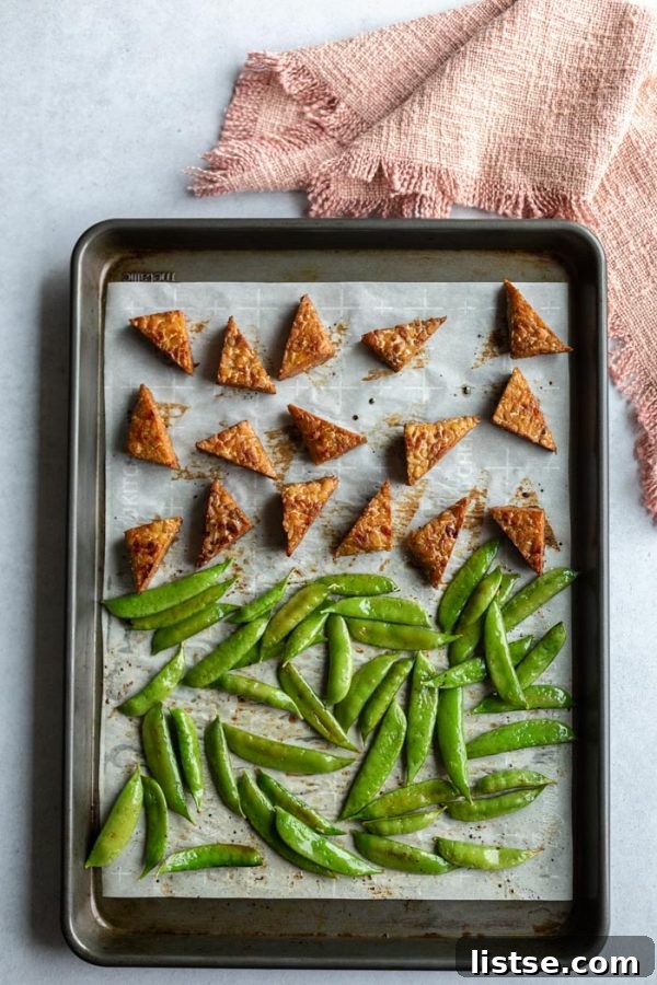 Tempeh Smokehouse Bowls 3 smoked tempeh and sugar snap peas arranged on a parchment-lined baking tray