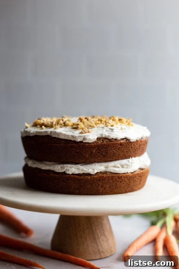 Iced vegan carrot cake on a elegant cake stand, surrounded by fresh carrots