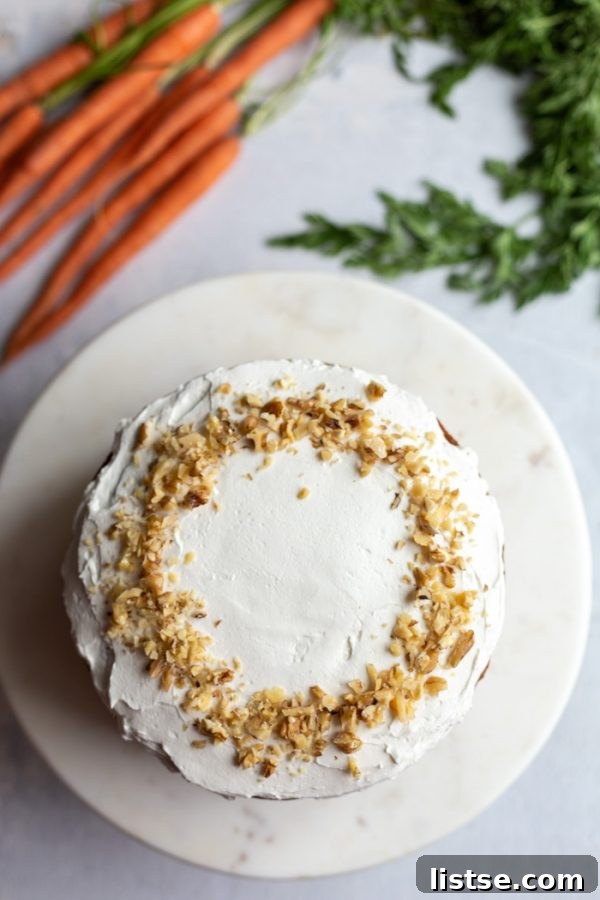 Top-down shot of a beautifully frosted vegan carrot cake, sprinkled with chopped nuts