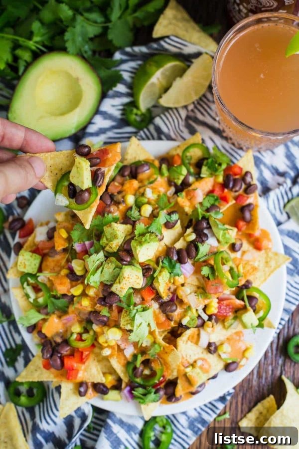 An epic platter of loaded vegan nachos, piled high with colorful toppings, perfect for sharing at parties