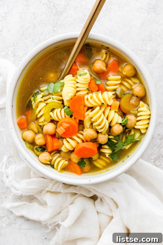 Golden Chickpea Noodle Hug 3 A steaming bowl of vegan chickpea noodle soup garnished with fresh parsley.