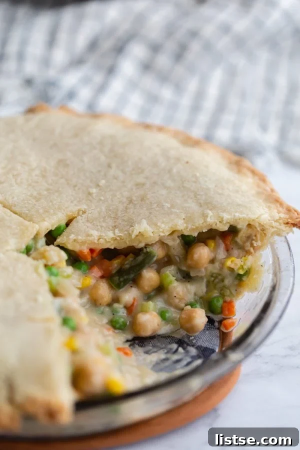 Hearty Vegan Chickpea Pot Pie 2 Close-up shot of a golden-brown vegan chickpea pot pie baking in a pie dish, steam gently rising.